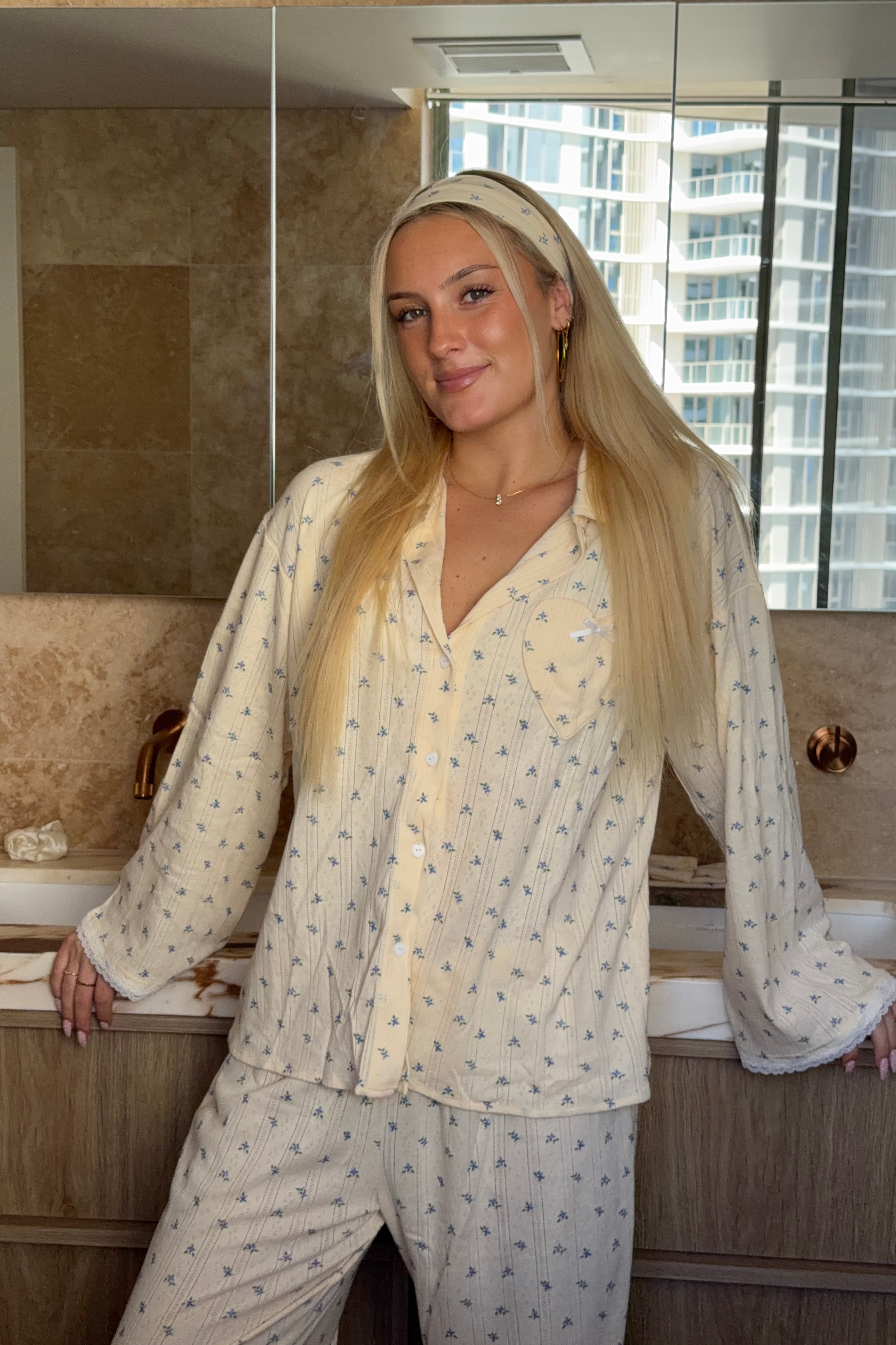 Woman in a patterned pajama set standing in a bathroom.