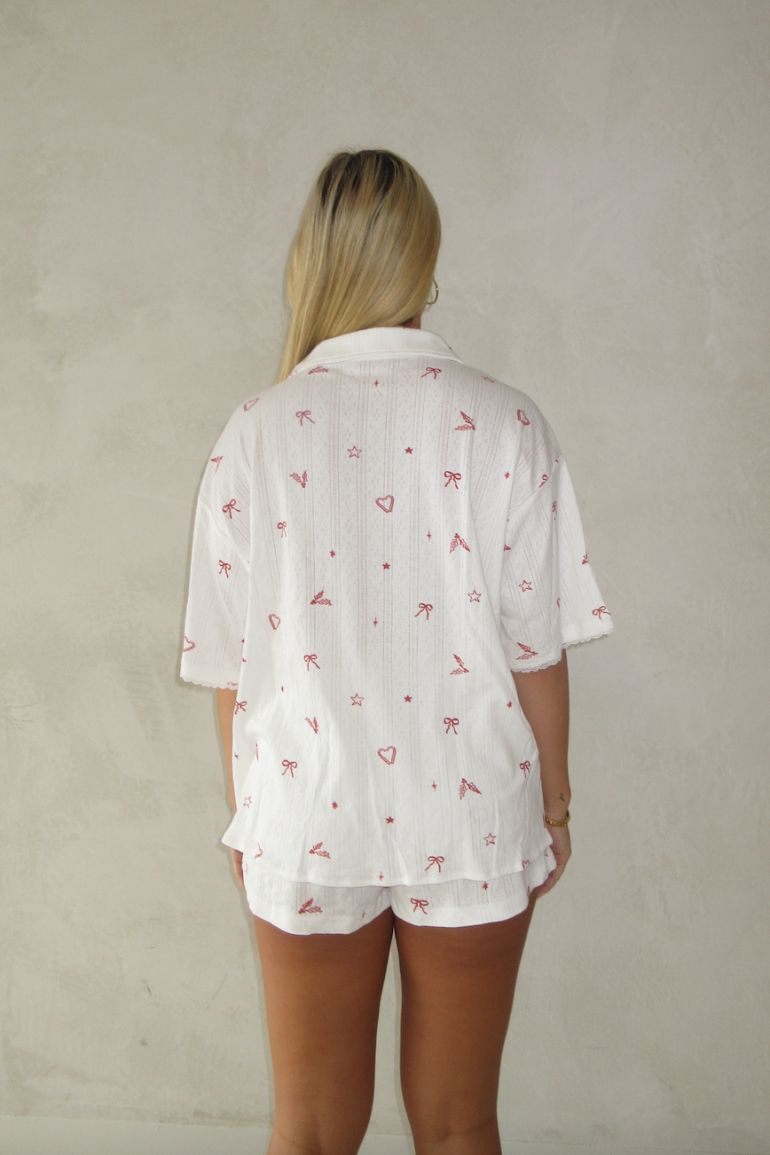 Person wearing a white patterned shirt and shorts against a plain background from the back view 