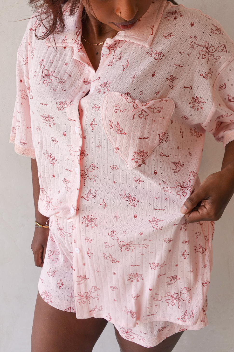 Person wearing a pink floral patterned shirt dress against a neutral background close up detail