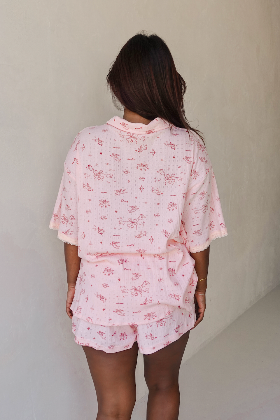 Person wearing a pink floral pajama set against a plain background from the back
