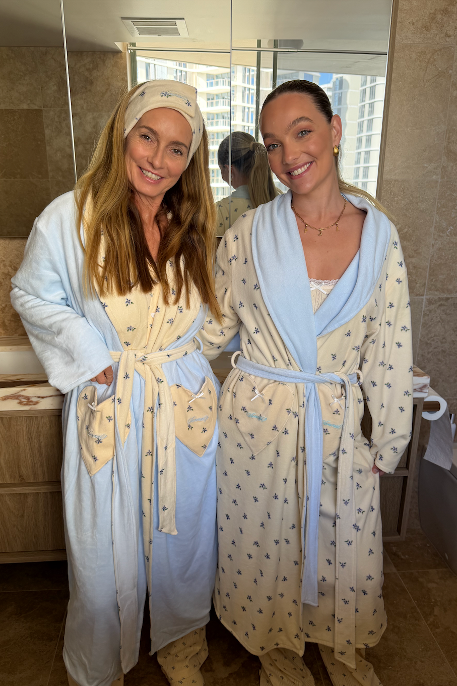 Mother & Daughter in matching bathrobes standing in a bathroom getting ready